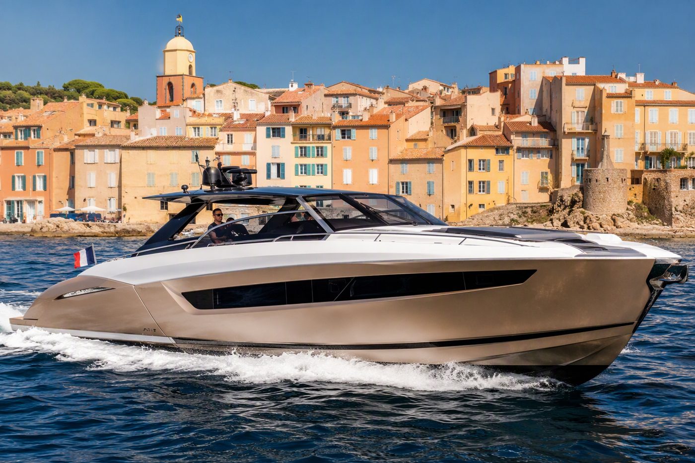 Solstice Runner — sleek luxury day cruiser passing a Mediterranean coastal town